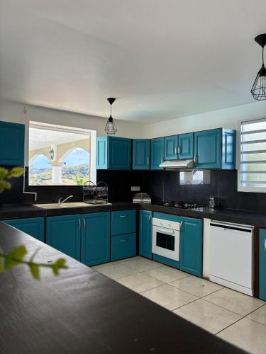 a kitchen with blue cabinets and white appliances at Villa Dulce Caliente au Vauclin in Le Vauclin