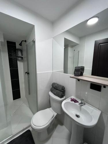 a white bathroom with a toilet and a sink at Hotel Lesus in Medellín