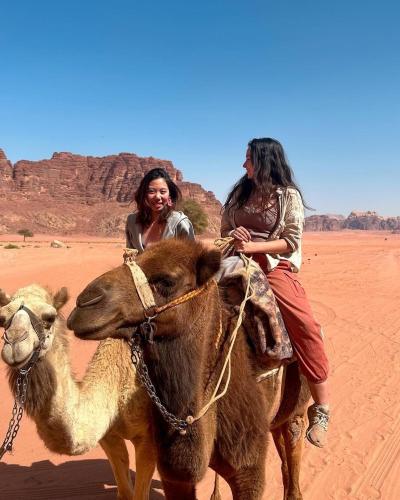 ワディ・ラムにあるDesert Timeの砂漠でラクダに乗っている2人の女性