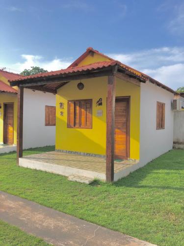 a small yellow and white house with a porch at Pousada Chale Joana in Alter do Chao