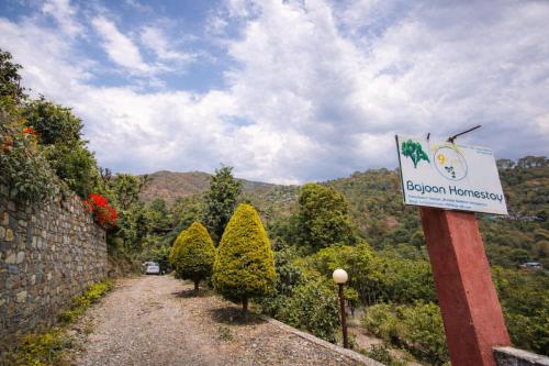 a sign on the side of a road with trees at Bajoon homestay in Bhīm Tāl