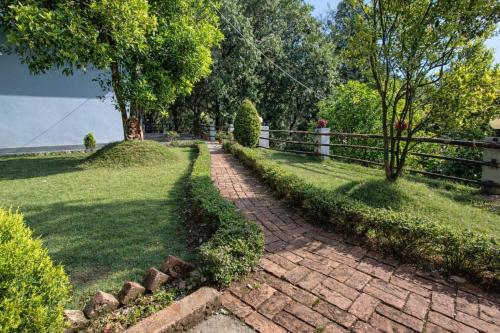 a brick path in a field with a fence at Bajoon homestay in Bhīm Tāl