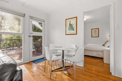 a white room with a table and chairs and a bed at Wattletree Cottage Halls Gap in Halls Gap