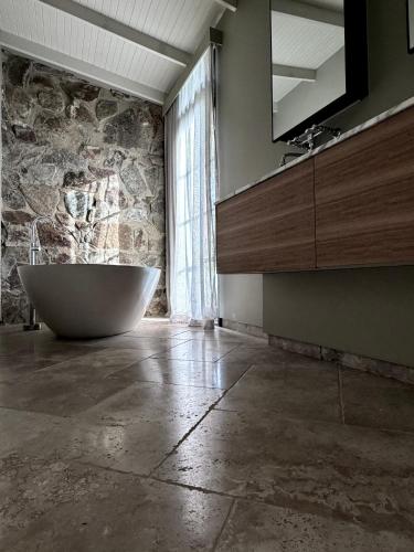 a bathroom with a sink and a tub in a stone wall at Frogs Pond in Red Hill