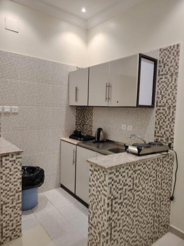 eine Küche mit weißen Schränken und einer Arbeitsplatte in der Unterkunft ميلاف للشقق المخدومة Milaf For Serviced Apartments in Al Shafa