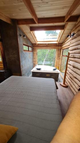 a bedroom with a large bed and a bath tub at Cabañas Refugio del Lago in El Cerrillo