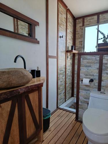 a bathroom with a toilet and a glass shower at Cabaña Rústica en Papudo in Papudo