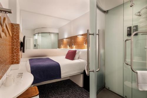 a bathroom with a bed and a sink and a mirror at BreakFree on Cashel, an Accor Hotel in Christchurch