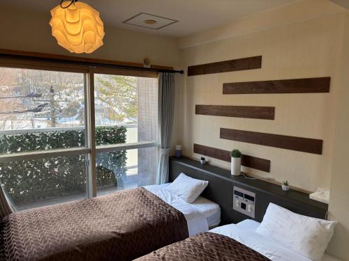 a bedroom with two beds next to a window at フューデイズコンドミニアム定山渓206号室 in Jozankei