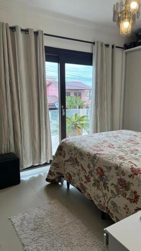 a bedroom with a bed and a large window at Apartamento de 2 quartos no centro de Garopaba in Garopaba