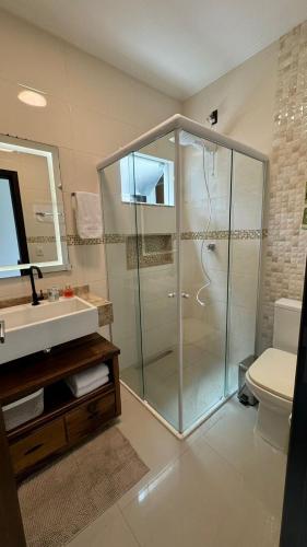a bathroom with a glass shower and a toilet at Apartamento de 2 quartos no centro de Garopaba in Garopaba