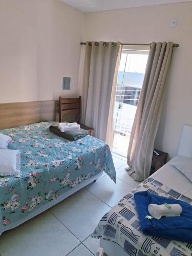 a bedroom with two beds and a sliding glass door at Pousada Morada in Aparecida