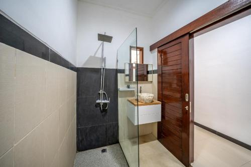 a bathroom with a glass door and a shower at The Dewi Pererenan Villa and Suite in Tumbak Bayuh