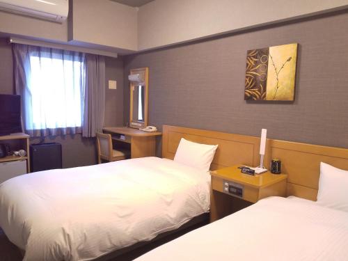a hotel room with two beds and a desk at Hotel Route-Inn Shiojirikita Inter in Shiojiri
