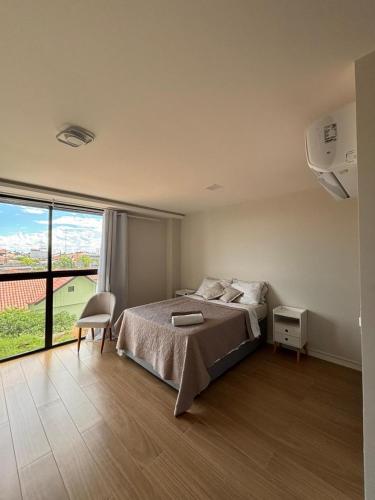 a bedroom with a bed and a large window at Flat Exclusivo com Rooftop e Piscina in Campina Grande