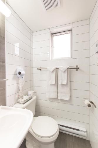 a white bathroom with a toilet and a sink at Travelodge by Wyndham Montreal Centre in Montréal