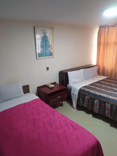a hotel room with two beds with pink sheets at Hotel Cristals Centro Bogota Estacion las Nieves Calle 18 numero 10 65 in Estación El Salto