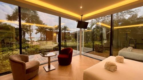 a room with a large window with a bed and chairs at Mirror Mirror Hotel Cafe & Restaurant in Ban Hang Ta Duk
