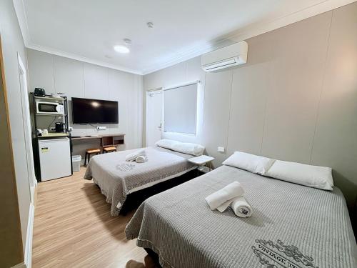 a hotel room with two beds and a television at Alpine Heritage Motel in Goulburn