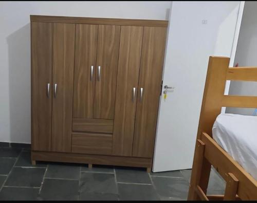 a bedroom with a wooden cabinet next to a bed at Quarto para 4 hóspedes in Itu