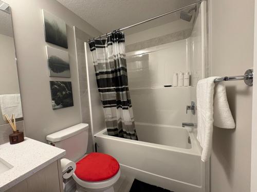 a bathroom with a shower and a toilet with a red seat at Beyond comfort - arriveYYC in YYC