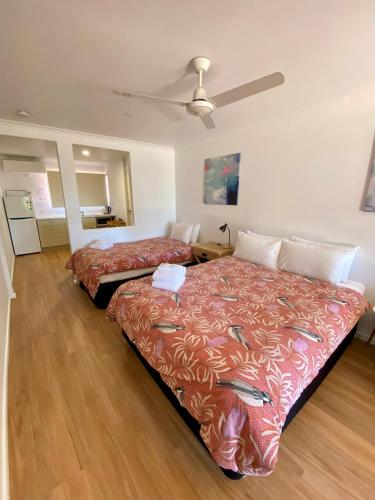 a bedroom with two beds and a ceiling fan at Sunlodge Caravan Park in Hervey Bay
