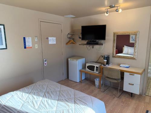ein Schlafzimmer mit einem Bett und einem Schreibtisch mit Fernseher in der Unterkunft Motel Rayalco in Laurier Station