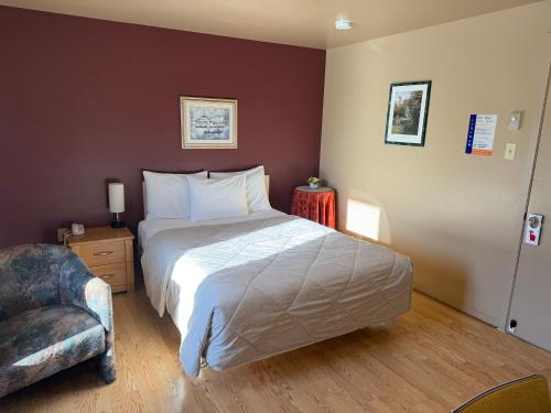 ein Schlafzimmer mit einem großen Bett und einem Stuhl in der Unterkunft Motel Rayalco in Laurier Station