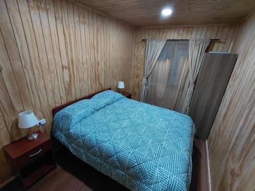 a bedroom with a bed with a blue comforter at Siloe in Coihaique