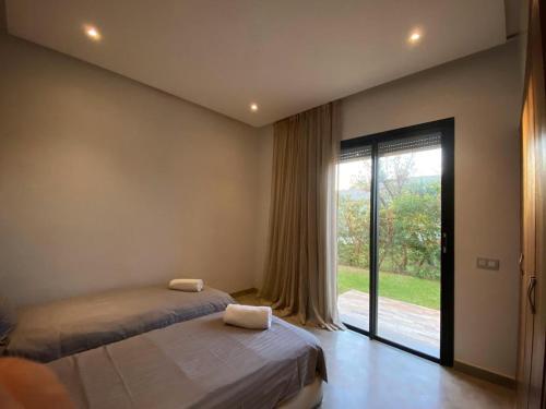 a bedroom with two beds and a large window at Villa nomad marrakech in Douar bel Rhanodour
