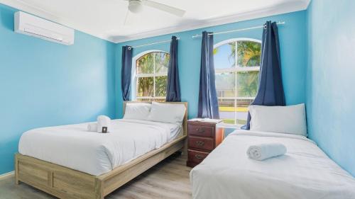 two beds in a room with blue walls and windows at Boater's Retreat - pet friendly, right off the M1 in Toormina