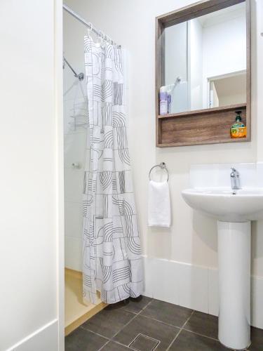 a bathroom with a shower curtain and a sink at Sunlodge Caravan Park in Hervey Bay