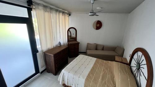 a bedroom with a bed and a couch and a window at Casa Braiden in Malucano