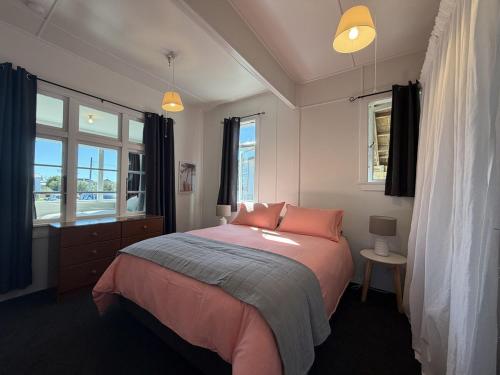 a bedroom with a bed with pink sheets and windows at Wilmas by the Bay in Riverton