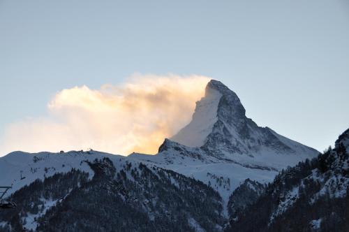 a mountain covered in snow with a sunset in the background at Apartments Styria in Zermatt