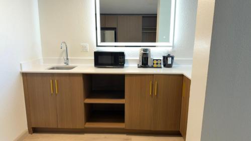a kitchen with a sink and a mirror at Holiday Inn Houston S - NRG Area - Med Ctr by IHG in Houston
