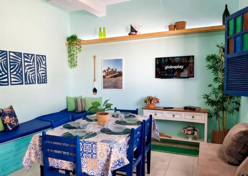 a dining room with a table and a blue couch at Berlinque Pet Friendly - Muito espaço perto do mar in Vera Cruz de Itaparica