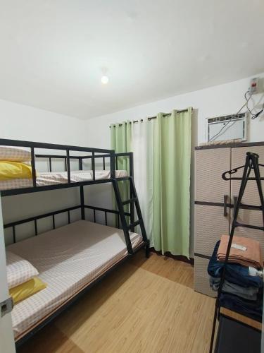 a room with two bunk beds and green curtains at Sorelle Haven II in Manolo Fortich