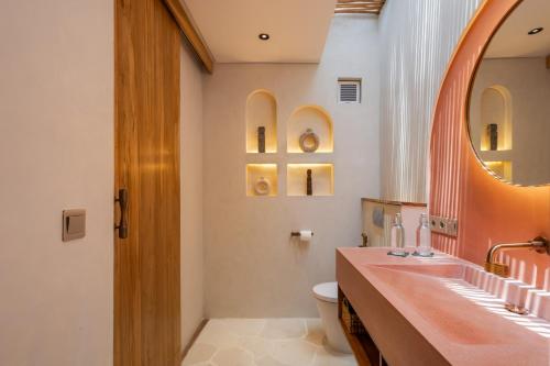 a bathroom with a sink and a toilet and a mirror at Bebas Suites - Uluwatu, Bali in Uluwatu