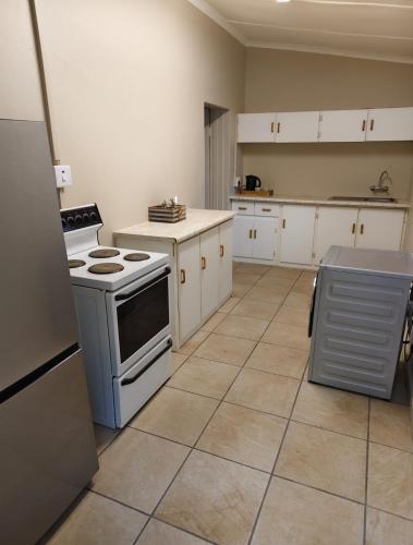 a kitchen with white cabinets and a stove top oven at 4 Houtjies verblyf in Orania