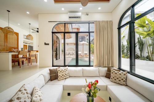 a living room with a white couch and large windows at Villa Arco Pererenan in Canggu