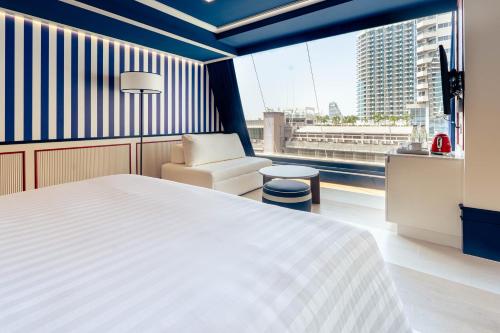 a bedroom with a bed and a chair and a large window at The Cruise Hotel in Pattaya