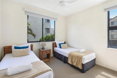 two beds in a room with two windows at Kings Row Apartments in Caloundra