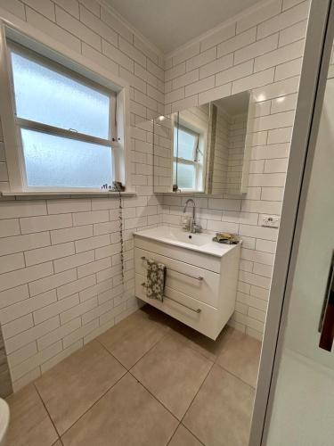 a white bathroom with a sink and a mirror at Sunbeam Cottage in Havelock North