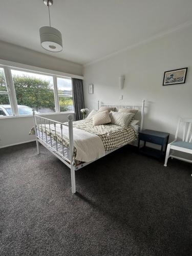 a bedroom with a white bed and a window at Sunbeam Cottage in Havelock North
