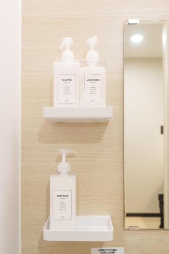 a bathroom with three bottles of soap and a mirror at 燕のお宿-The Swallow's Inn- in Kumamoto