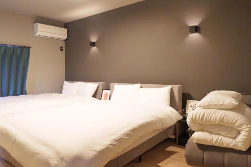 two beds in a room with white sheets and pillows at 燕のお宿-The Swallow's Inn- in Kumamoto