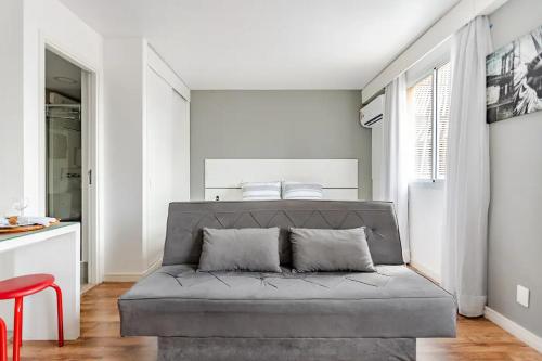 a living room with a gray couch and a red stool at Flat Hotel Vila Olímpia in São Paulo