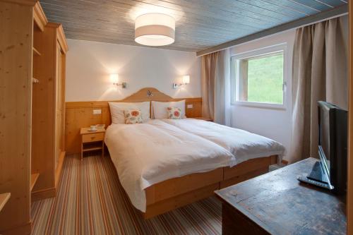 a bedroom with a large bed and a television at Apartments Styria in Zermatt