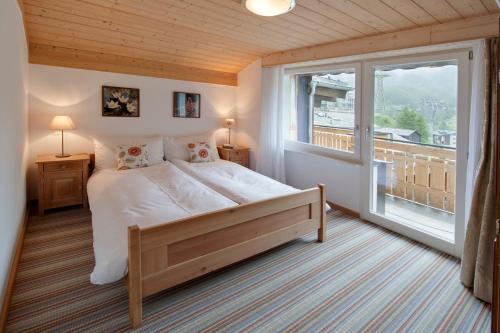 a bedroom with a large bed and a large window at Apartments Styria in Zermatt